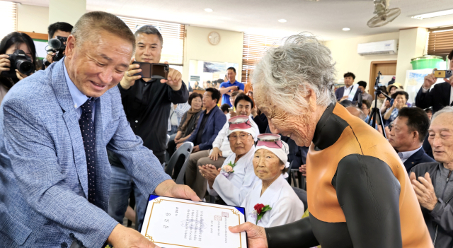 25일 오후 제주시 한림읍 귀덕2리어촌계회관에서 열린 사상 첫 해녀 은퇴식에서 92살 김유생 해녀가 김성근 어촌계장으로부터 공로상을 받고 있다. 귀덕2리어촌계는 이날 은퇴한 9명의 해녀 모두에게 공로상을 수여했다. 연합뉴스