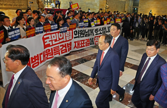 국민의힘 추경호 원내대표를 비롯한 의원들이 28일 오후 국회에서 열린 본회의에 참석하고 있다. 그 뒤로 야당 의원들이 해병대원 특검법 재표결 찬성을 촉구하고 있다. 연합뉴스