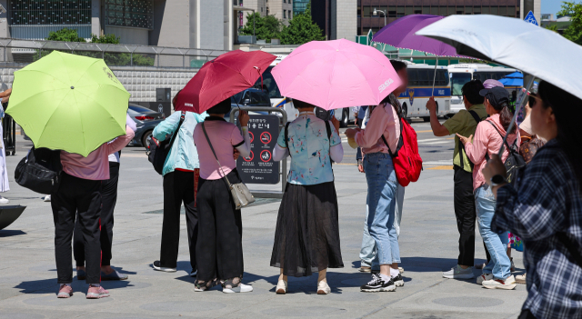 지난 3일 오후 서울 종로구 광화문광장에서 관광객들이 양산을 쓰고 있다. 연합뉴스