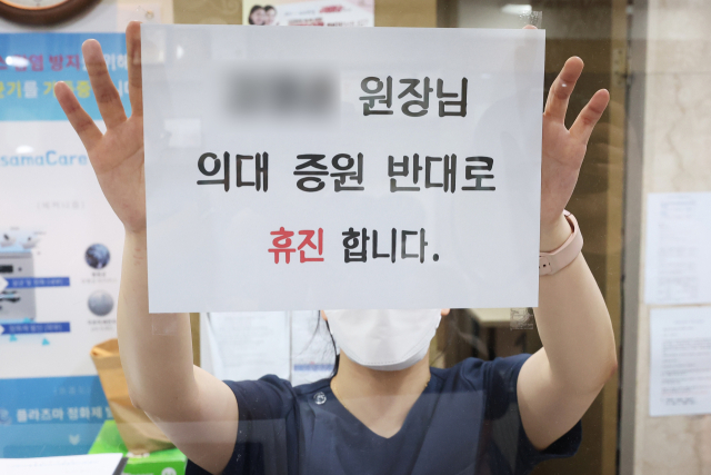 의료계 집단 휴진을 하루 앞둔 17일 오후 경기도 한 의원에서 관계자가 휴진 안내문을 붙이고 있다. 이 병원은 두 명의 의사 중 한 명만 휴진한다. 연합뉴스