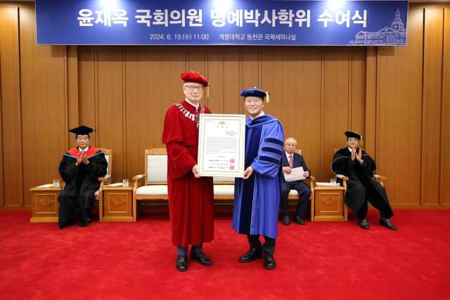 윤재옥 국회의원(오른쪽)이 19일 신일희 계명대 총장으로부터 명예 행정학 박사학위를 받고 있다. 연합뉴스