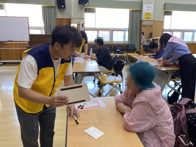 부산 기장군지역사회보장협의체 위원이 기장군노인복지관에서 도로명주소 SOS 스티커를 안내하고 있다. [사진=기장군]