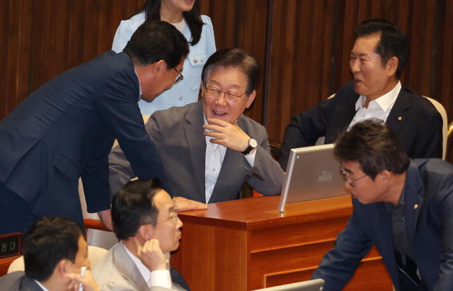 더불어민주당 이재명 전 대표(가운데)가 3일 오후 국회 본회의장에서 열린 경제 분야 대정부질문에 참석해 동료 의원과 대화하고 있다. 연합뉴스