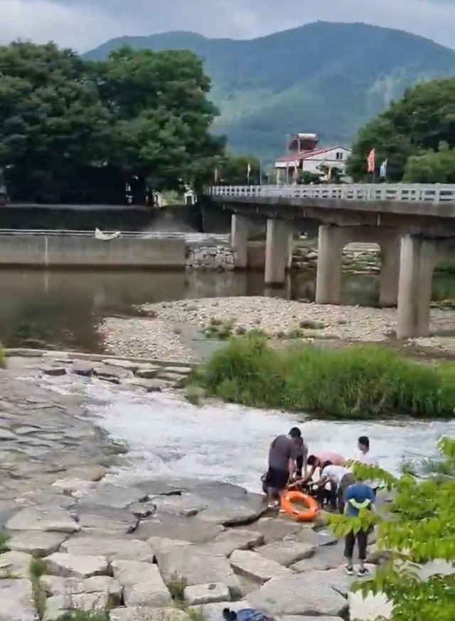 손진복 씨가 밀양시 물놀이 안전관리 요원과 함께 지난 5일 밀양시 단장면 단장숲유원지 아래 하천에 빠진 50대 여성을 구조하고 있는 모습. 밀양시 제공