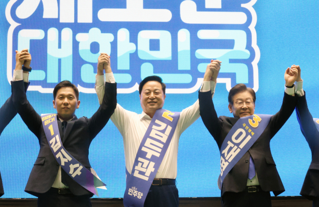 더불어민주당 새 지도부 선출을 위한 전당대회를 앞두고 20일 제주시 한라체육관에서 열린 합동연설회에서 김지수·김두관·이재명 대표 후보(왼쪽부터)가 손을 맞잡고 포토타임을 갖고 있다. 연합뉴스