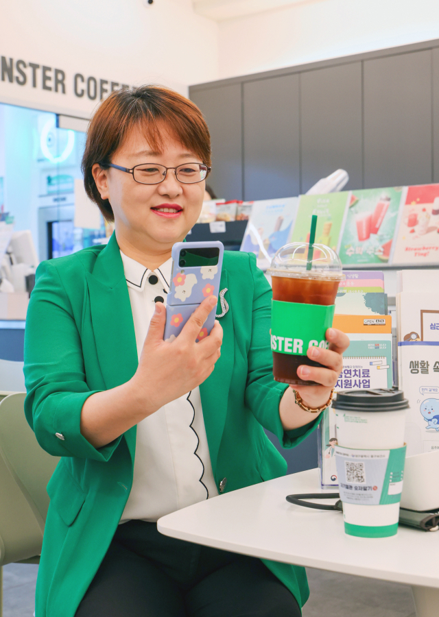 황석선 중구보건소장이 몬스터 커피에서 휴대폰으로 컵홀더에 있는 QR코드를 찍고 있다. QR코드를 찍으면 