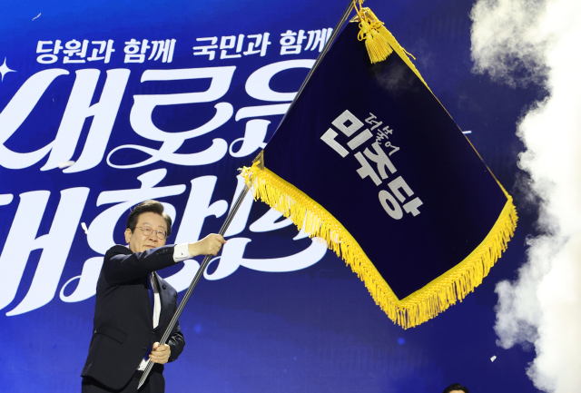 더불어민주당 당대표 연임에 성공한 이재명 신임 당대표가 18일 오후 서울 송파구 올림픽공원 KSPO돔에서 열린 전국당원대회에서 박찬대 대표 직무대행 겸 원내대표로부터 전달받은 당기를 흔들고 있다. 연합뉴스