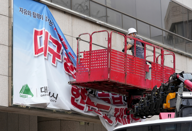 28일 오후 대구시청 동인청사에서 현수막 업체 관계자가 외벽에 붙어있던 대구·경북 행정통합 관련 홍보 현수막을 철거하고 있다. 김영진 기자 kyjmaeil@imaeil.com