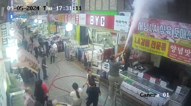 지난 5일 오후 5시 50분쯤 달서구 서남신시장 상가 캐노피 위에 설치된 에어컨 실외기에서 불이 나 상인회 회 관계자들과 의용소방대원 등이 진화작업에 나서고 있는 모습. 대구 달서소방서 제공