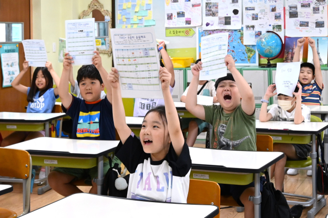초등학교 여름방학이 끝나고 개학을 맞은 지난 8월 19일 대구 달서구 덕인초등학교 2학년 학생들이 선생님께 방학숙제를 들어보이며 환하게 웃고있다. 안성완 기자 asw0727@imaeil.com