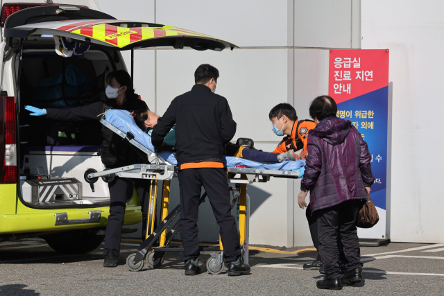 8일 서울 시내의 한 대학병원 응급의료센터로 이송되는 환자 옆에 응급실 지연 안내문이 놓여 있다. 연합뉴스