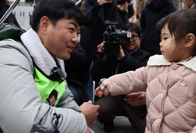 국내에는 치료법이 없는 희귀병을 앓고 있는 네 살 딸 사랑이의 치료비용을 위해 전국 곳곳을 돌며 후원을 요청하고 있는 전요셉 씨가 29일 오후 최종 목적지인 서울 광화문광장에 도착, 마중 나온 사랑이에게 꽃을 받고 있다. 연합뉴스