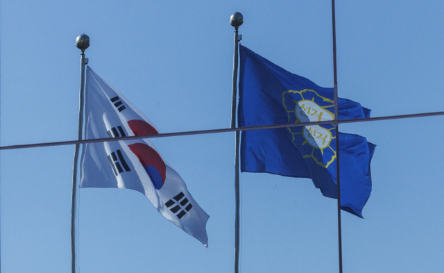 6일 오전 경기도 과천 중앙선거관리위원회에 창문에 태극기와 선관위 깃발이 펄럭이는 모습이 일그러져 투영돼 있다. 중앙선관위는 이날 선거위원 회의를 거쳐 비상계엄 상황 때 계엄군이 선관위 청사를 점거한 것과 관련, 