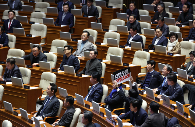 7일 국회 본회의장에서 야당 의원이 윤석열 대통령 처벌 촉구 팻말을 들고 있다. 이날 본회의는 윤 대통령 탄핵소추안 등을 표결할 예정이다. 연합뉴스