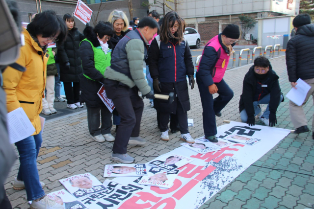 9일 오전 10시 국민의힘 대구시당 앞에서 윤석열퇴진대구시국회의는 표결에 불참한 국민의힘 소속 대구 국회의원 12명의 사진을 바닥에 놓고 발로 짓밟았다. 윤석열퇴진대구시국회의 제공