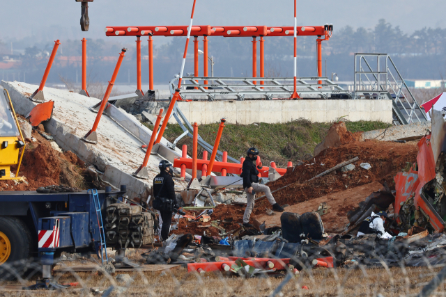 30일 전남 무안군 무안국제공항 제주항공 여객기 충돌 폭발 사고 현장에서 경찰 과학수사대가 활주로 인근의 방위각 시설(로컬라이저)을 살피고 있다.. 방위각 시설은 공항의 활주로 진입을 돕는 역할을 하는 일종의 안테나로, 흙으로 된 둔덕 상부에 있는 콘크리트 기초와 안테나가 서 있는 구조다. 연합뉴스