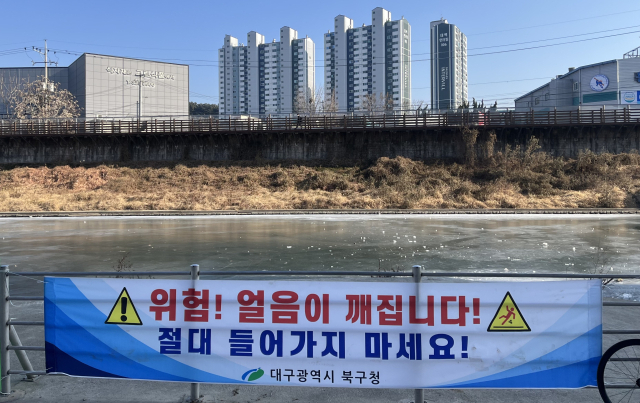지난 23일 초등학생 한 명이 숨지는 사고가 발생한 팔거천 인근. 사고 위험이 커 하천에 접근해선 안 된다고 알리는 현수막 뒤에 새하얀 얼음이 넓게 펼쳐져 있다. 정두나 기자