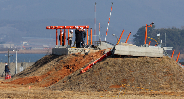 지난달 26일 오후 전남 무안국제공항에서 항공철도사고조사위원회, 경찰, 국과수 관계자들과 제주항공 참사 유가족 대표단이 방위각 시설(로컬라이저)을 살펴보고 있다. 연합뉴스