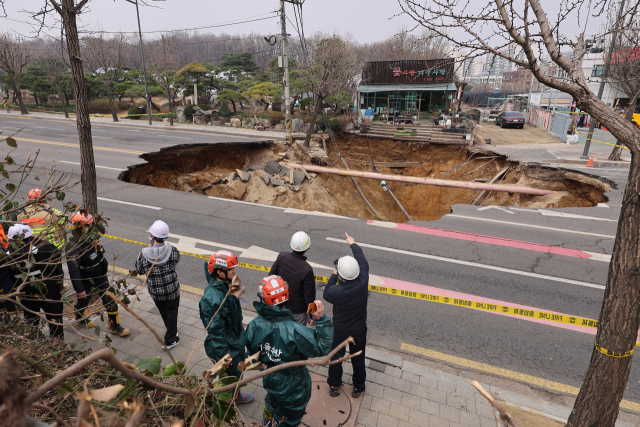 25일 강동구 대명초등학교 도로에서 전날 발생한 대형 땅꺼짐 현장의 모습. 전날 오후 명일동 대명초등학교 인근 사거리에서 발생한 지름 20ｍ, 깊이 18ｍ가량의 대형 싱크홀에 오토바이 운전자 1명이 빠져 사망했다. 연합뉴스