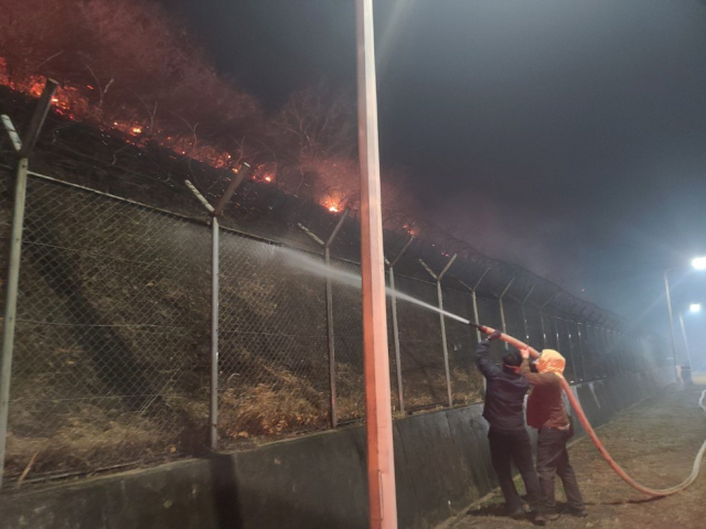 지난 25일 경북 청송군 경북북부 제2교도소에서 교도소 인근까지 번진 산불을 막기 위해 직원들이 물을 뿌리고 있다. 연합뉴스