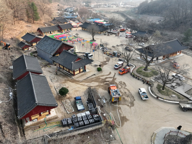 26일 경북 청송 주왕산 국립공원 내 대전사에서 관계자들이 주왕산에 번지는 산불로부터 사찰을 보호하기 위해 미리 물을 뿌리는 예비 중수 작업으로 분주하다. 연합뉴스