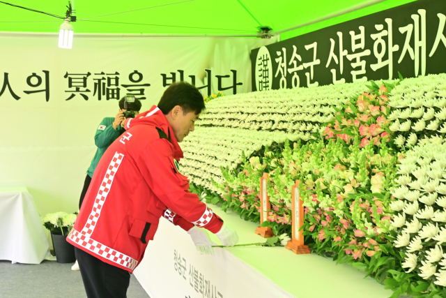 27일 청송군 보건의료원 장례식장 앞 주차장에 마련된 산불화재사고 희생자 합동분향소에 윤경희 청송군수가 헌화를 하는 모습. 청송군 제공