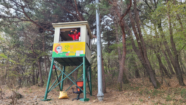 윤두영 산불감시원이 대왕재 감시탑 위에서 망원경으로 팔공산을 살피고 있다. 남정운 기자