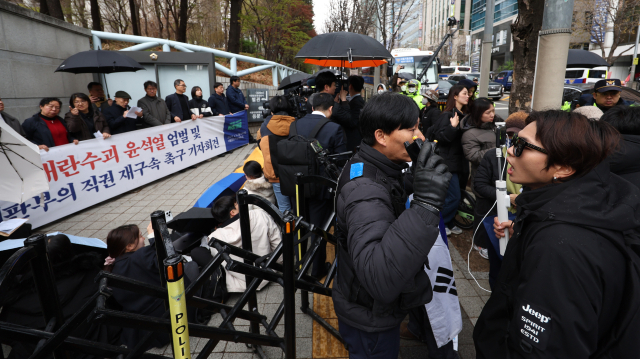 내란 우두머리 혐의로 기소된 윤석열 전 대통령의 첫 형사재판이 열린 14일 서울 서초구 서울중앙지방법원 앞에서 경찰 관계자들이 윤 전 대통령 엄벌 촉구 기자회견을 하는 시민단체와 윤 전 대통령 지지자들을 분리하고 있다. 연합뉴스