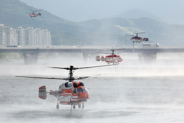 지난달 29일 진화된 대구 북구 함지산 산불이 재발화한 가운데 1일 오전 산림청, 소방 소속 헬기들이 진화작업을 위해 인근 금호강에서 물을 채우고 있다. 연합뉴스