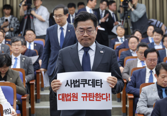대법원이 이재명 더불어민주당 대선후보의 공직선거법 위반 혐의 2심 무죄판결을 파기 환송한 1일 서울 여의도 국회에서 열린 긴급의원총회에서 박찬대 당 대표 직무대행 겸 원내대표가 대법원 규탄 손팻말을 들고 있다. 연합뉴스