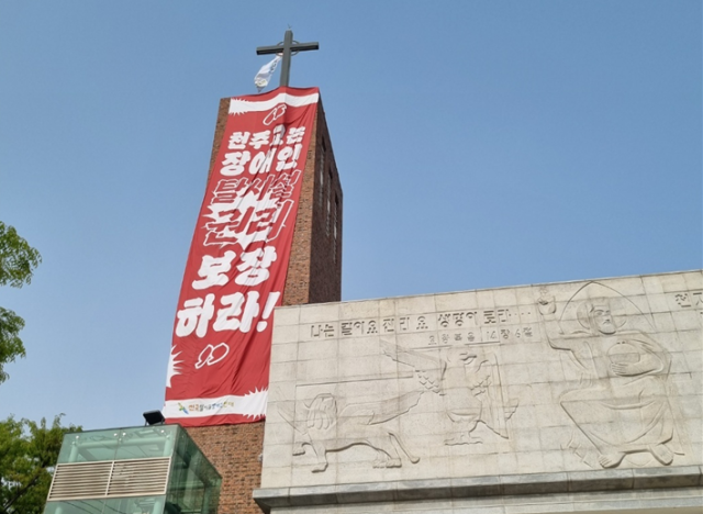 지난 18일 서울 혜화동 성당에 무단 침입해 대형 현수막을 건 전장연. 천주교