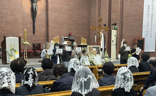 지난 24일 경기 수원 정자동성당에 마련된 프란치스코 교황 빈소에서 기도하는 신자들을 앞에 두고 전장연이 탈시설 촉구를 위한 기습 집회를 연 모습. 천주교