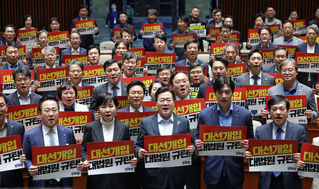 더불어민주당 박찬대 원내대표를 비롯한 의원들이 4일 국회에서 열린 긴급 의원총회에서 대법원 규탄 팻말을 들고 구호를 외치고 있다. 연합뉴스