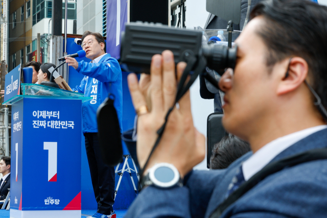 더불어민주당 이재명 대선 후보가 14일 경남 창원시 상남분수광장에서 열린 집중 유세에서 지지를 호소하는 가운데 경호원이 경계 근무를 서고 있다. 연합뉴스