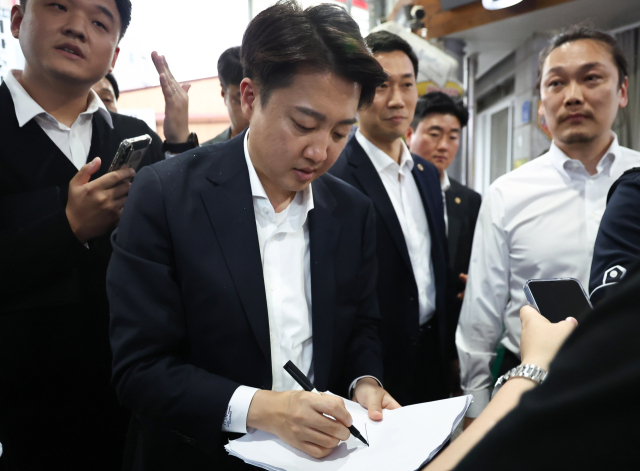 개혁신당 이준석 대선 후보가 16일 충청남도 천안중앙시장을 방문, 한 시민이 건넨 종이에 사인하고 있다. 연합뉴스