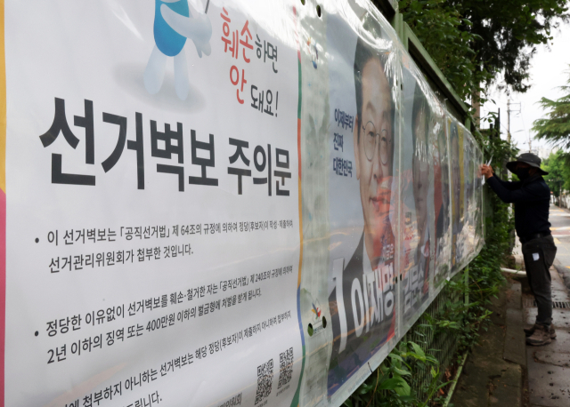 제21대 대통령 선거 벽보 부착을 시작한 15일 전북선거관리위원회 관계자가 전주시 완산구 효자동의 한 아파트 입구에 후보자 벽보를 붙이고 있다. 연합뉴스