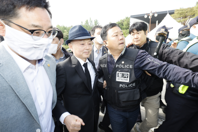 제45주년 5·18 민주화운동 기념식이 열린 18일 오전 광주 북구 운정동 국립 5·18 민주묘지 민주의문 앞에서 시민들의 항의를 받은 안창호 국가인권위원장이 경호를 받으며 돌아가고 있다. 연합뉴스