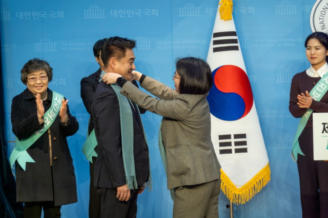 22대 총선을 앞뒀던 2024년 2월 15일 새진보연합(기본소득당 주도로 사회민주당과 열린민주당이 구성했던 선거연합정당)의 2호 인재로 영입된 최혁진 전 문재인 정부 청와대 사회적경제비서관에게 용혜인 기본소득당 대표가 목도리를 매어주고 있다. 기본소득당