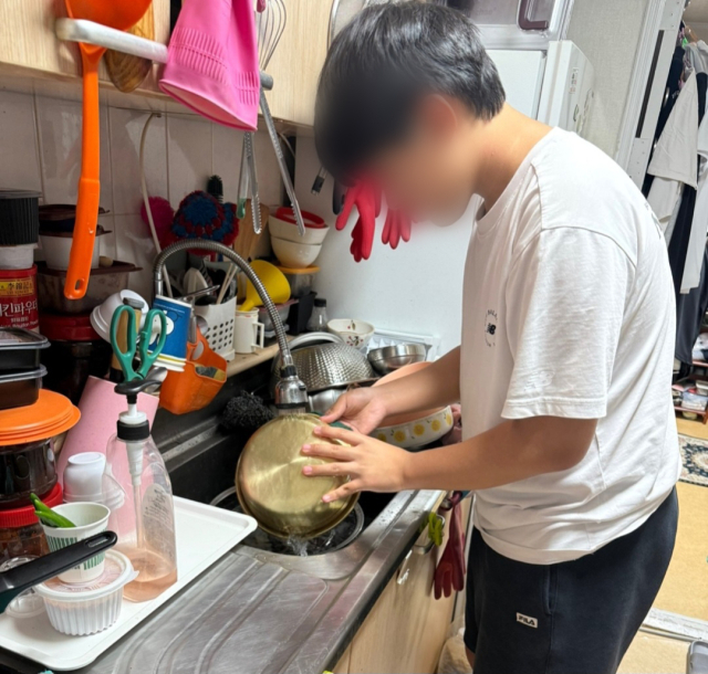 지난 10일 우민 군이 집에서 설거지를 하는 모습. 부모가 차려주는 밥을 먹어야 할 12살의 나이에 우민 군은 요리를 배웠다. 라면을 끓이며 불을 다루는 법을 익혔고, 콩나물국과 오뎅탕도 만들어 아버지 식사를 챙기고 있다. 아버지 영석 씨 제공