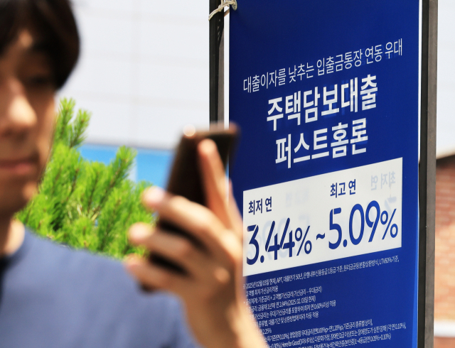 15일 서울 시내 은행 앞 대출 홍보물을 지나는 시민. 연합뉴스