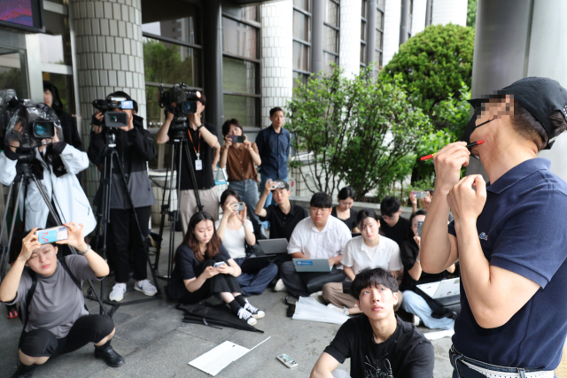 지난해 서울 강남역 의대생 살인 사건 피해자의 아버지가 20일 서울 서초경찰서에서 사체손괴 혐의로 가해자 최모씨를 고소한 뒤 취재진 앞에서 자신의 목과 얼굴에 사인펜으로 딸의 상흔을 표시하며 살해 과정을 직접 재연하고 있다. 연합뉴스