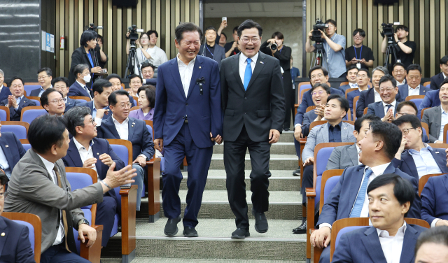 더불어민주당 당대표 후보인 정청래(왼쪽)·박찬대 의원이 24일 서울 여의도 국회에서 열린 의원총회에 나란히 손을 잡고 참석하고 있다. 연합뉴스