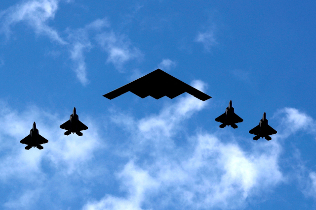 미 공군의 B-2 스피릿 스텔스 폭격기(중앙)가 F-22 랩터 전투기 4대의 호위를 받으며 비행 중인 모습. 로이터·연합뉴스