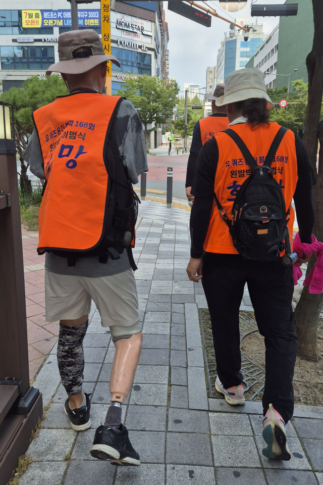 오른발 의족을 한 이범식 박사(사진 왼쪽)가 7일 오후 광주광역시청 앞에서 서포터즈들과 걷고 있는 모습. 이범식 서포터즈 김선완 단장 제공.