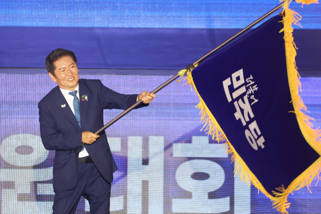 더불어민주당 정청래 신임 당대표가 2일 고양 킨텍스에서 열린 전국당원대회에서 김병기 당대표 직무대행 겸 원내대표로부터 받은 당기를 흔들고 있다. 연합뉴스