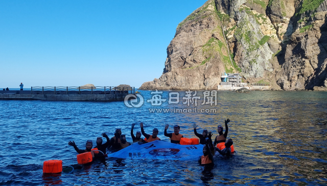 8일 독도에서 오영훈 제주도지사와 제주 해녀들이 바다에 입수해 대형태극기를 펼치며 환호하고 있다. 조준호 기자
