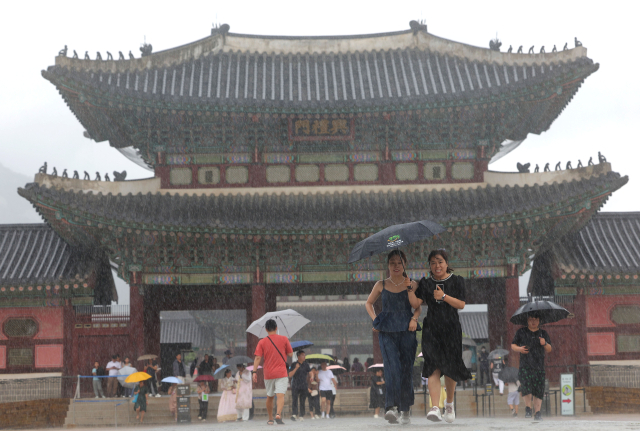 6일 비가 내리는 서울 경복궁에서 외국인 관광객들이 발걸음을 재촉하고 있다. 연합뉴스