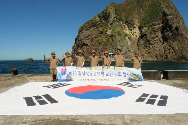 경북교육청 교원 독도 탐사단이 지난달 28일 대형 태극기 앞에서 독도를 지키자고 외치며 포즈를 취하고 기념 촬영하고 있다. 경북교육청 제공
