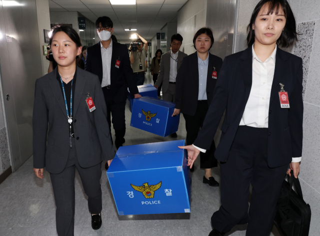 서울경찰청 금융범죄수사대 전담수사팀 관계자들이 11일 주식 차명거래 혐의를 받는 이춘석 의원의 국회 사무실 압수수색을 마친 뒤 압수품을 들고 의원실을 나서고 있다. 연합뉴스