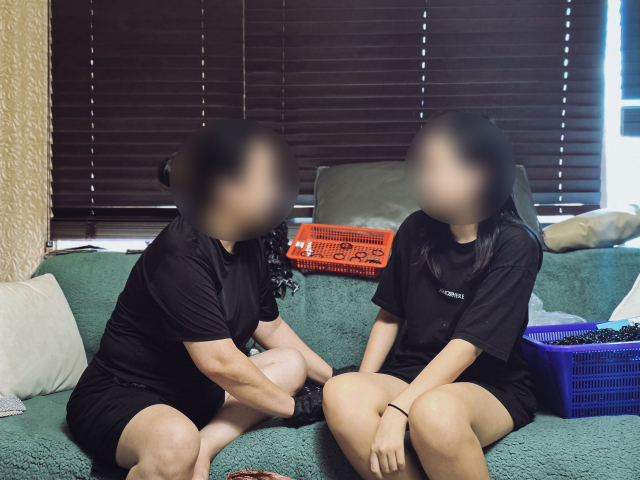 골괴사증으로 거동이 어려운 강정연(51·가명, 왼쪽) 씨가 부업 일을 하는 소파에서 사춘기를 겪는 둘째 딸을 바라보고 있다. 김지효 기자